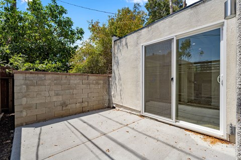 A concrete patio area with a glass door and a wall.