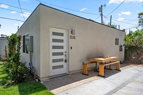 A small building with a door and a bench outside.