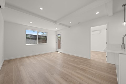 A spacious room with wooden flooring and white walls.