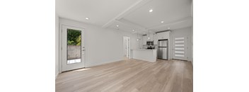 A spacious kitchen with wooden flooring and white walls.