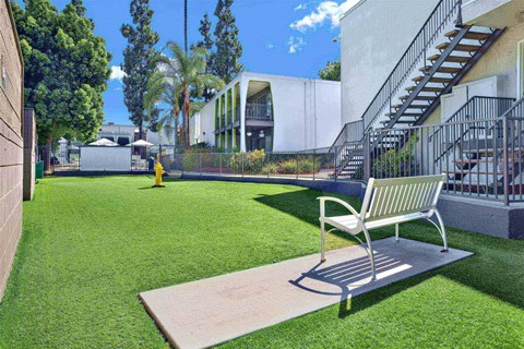 A park bench sits on a concrete slab in a grassy area.