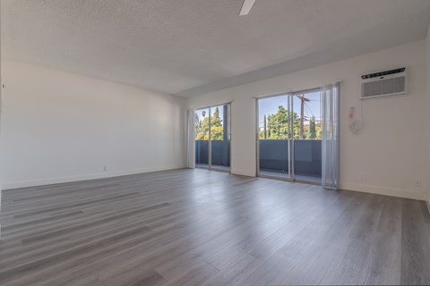 A spacious room with wooden flooring and sliding glass doors.