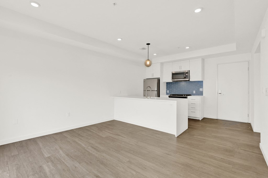 a living room with white walls and a kitchen