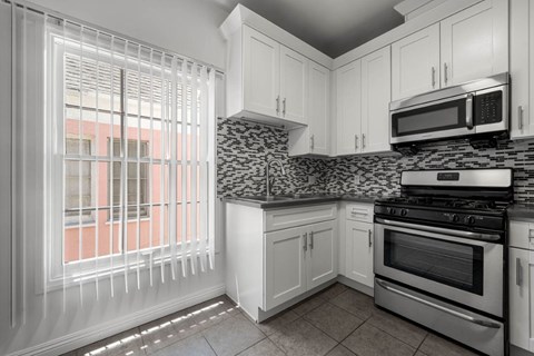 A kitchen with white cabinets and a black and white counter top.