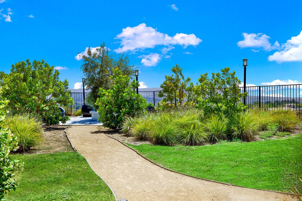 a walkway through a park with trees and grass at Monterra Ridge Apartments, Canyon Country, California