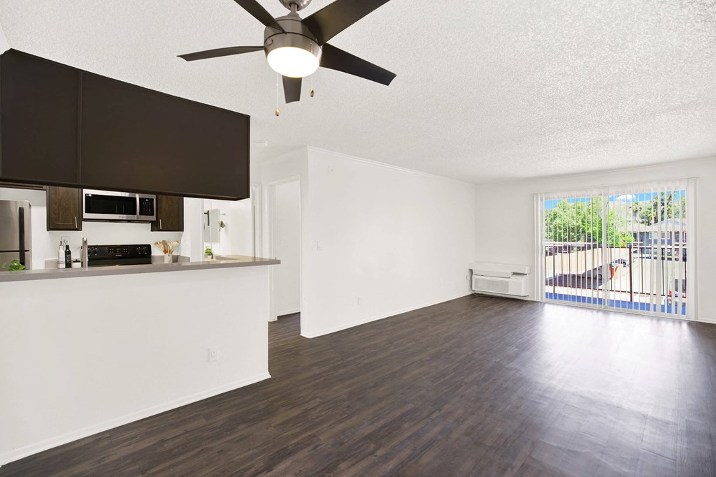 an empty living room with a kitchen and a ceiling fan at Monterra Ridge Apartments, Canyon Country, California