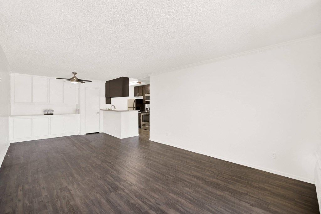 an empty living room and kitchen with white walls and wood flooring at Monterra Ridge Apartments,California