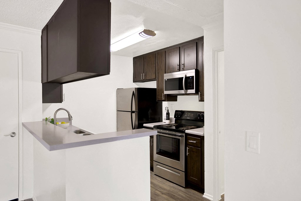 a kitchen with stainless steel appliances and dark cabinets at Monterra Ridge Apartments, California