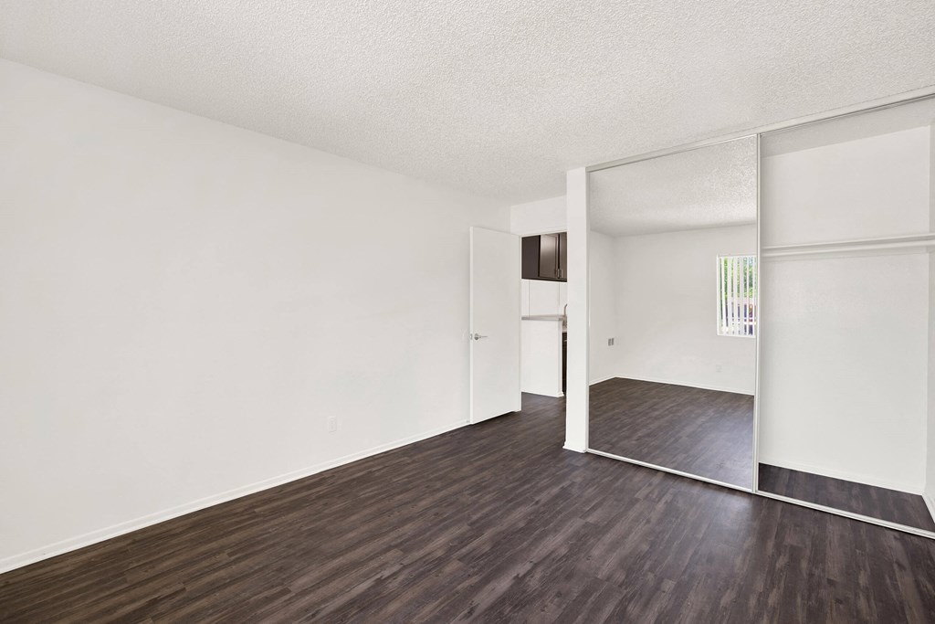 an empty living room with white walls and wood floors at Monterra Ridge Apartments, Canyon Country, California