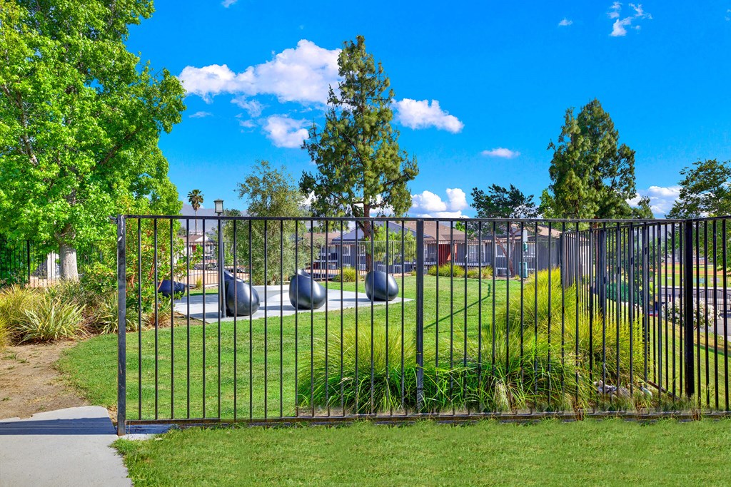a playground in a park behind a metal fence at Monterra Ridge Apartments, Canyon Country ,91351