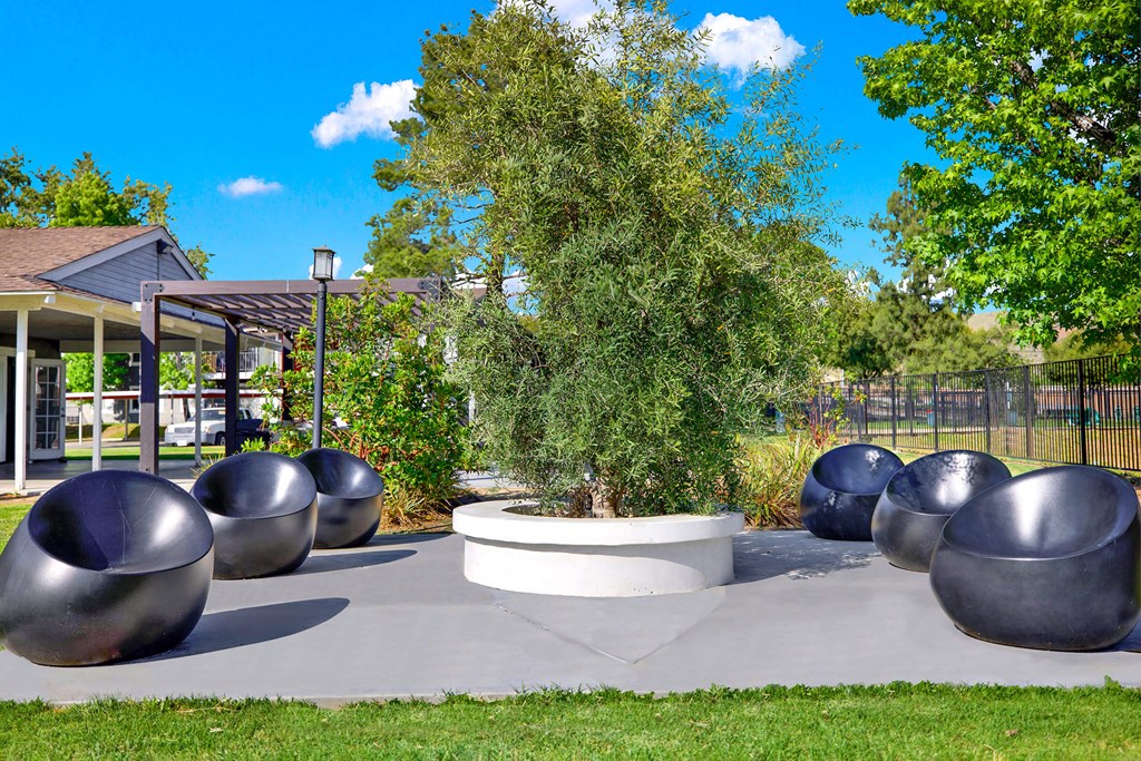 a seating area with metal benches and a tree at Monterra Ridge Apartments, Canyon Country