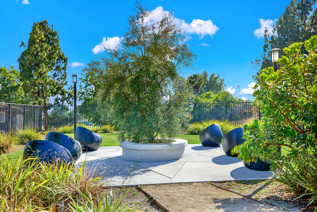 a seating area in a garden with trees and plants at Monterra Ridge Apartments,California