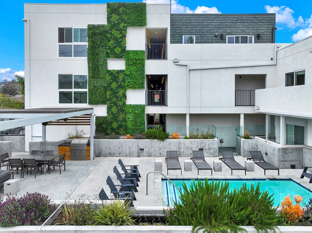 a white building with a pool and chairs in front of it