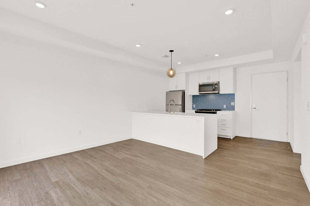 a living room with white walls and a kitchen