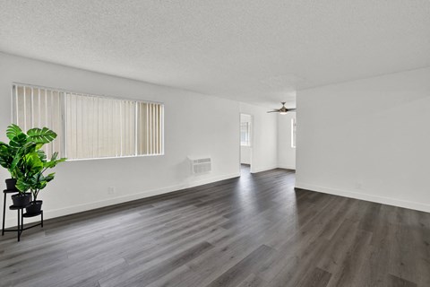 the living room and dining room of an apartment with white walls and wood flooring at Sunset Square Apartments, West Covina, California, 91790