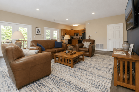 A living room with brown leather furniture and a flat screen TV mounted on the wall.