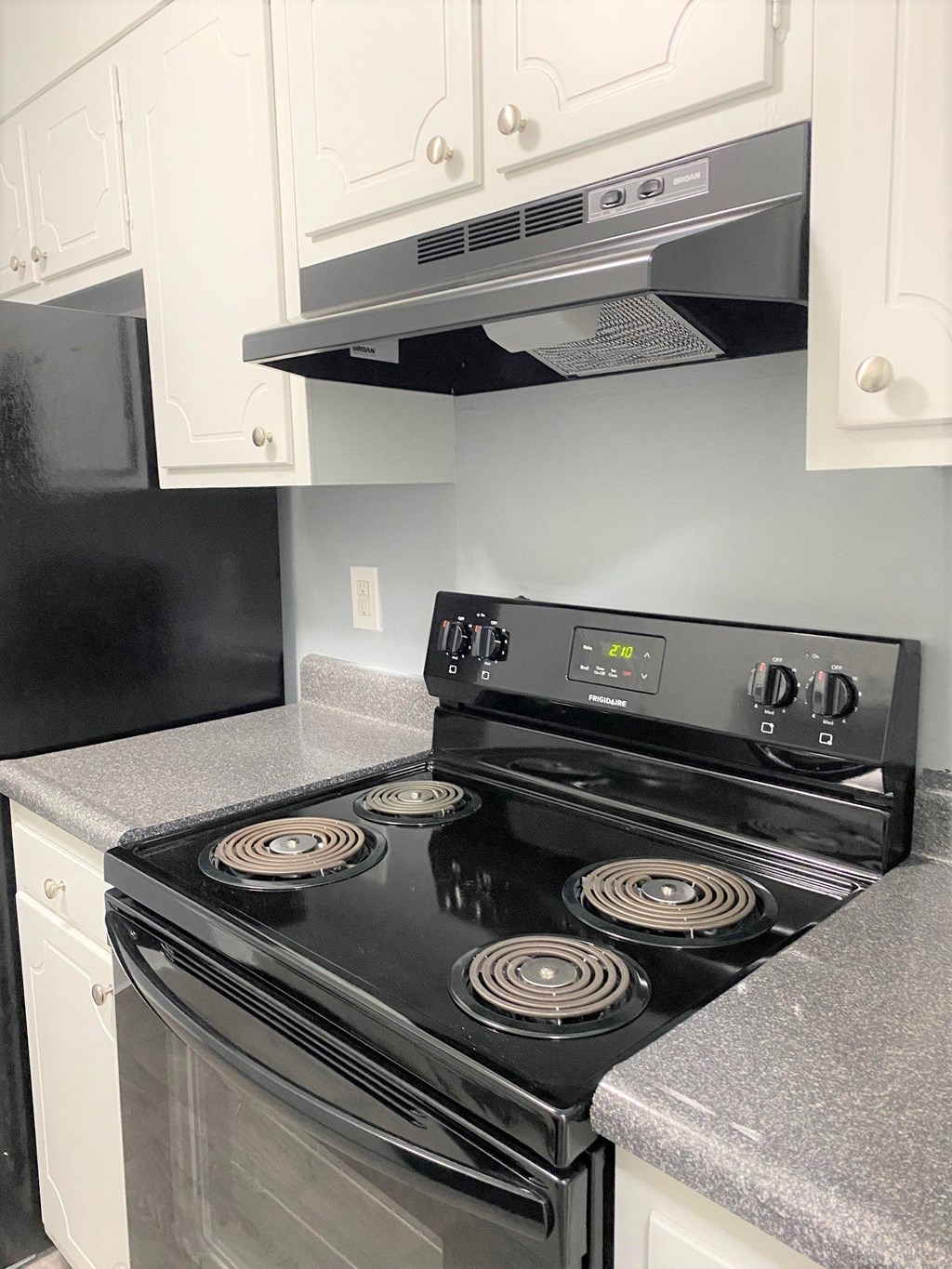 a kitchen with white cabinets and a black stove