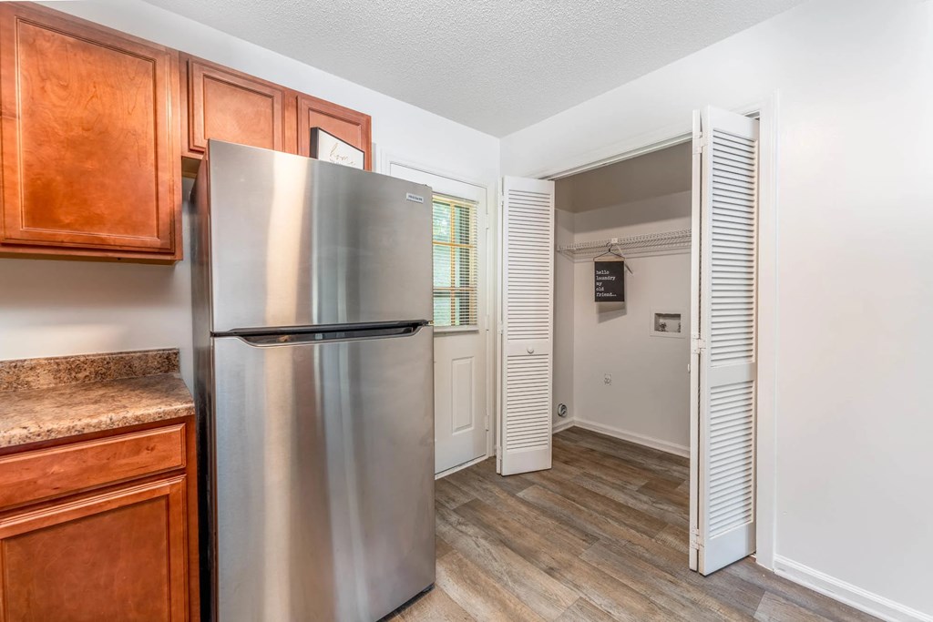 A kitchen with a stainless steel refrigerator and wooden cabinets.