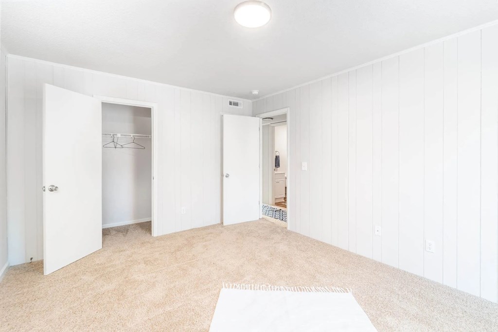 A white room with a rug on the floor and a door on the left.