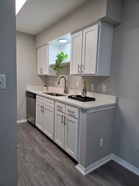 A kitchen with white cabinets and a black countertop.