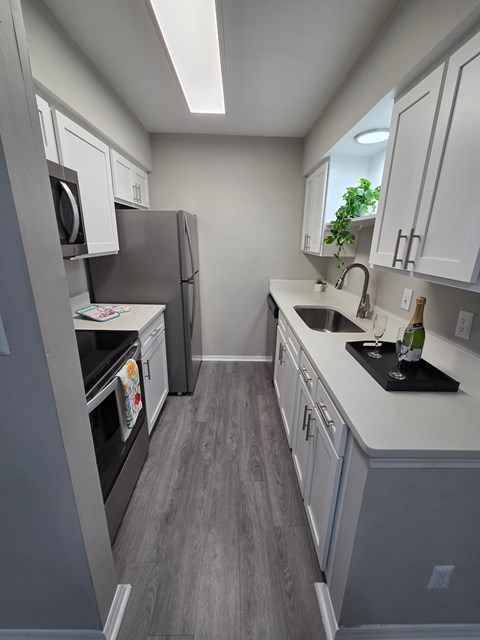 A kitchen with a refrigerator, oven, and sink.