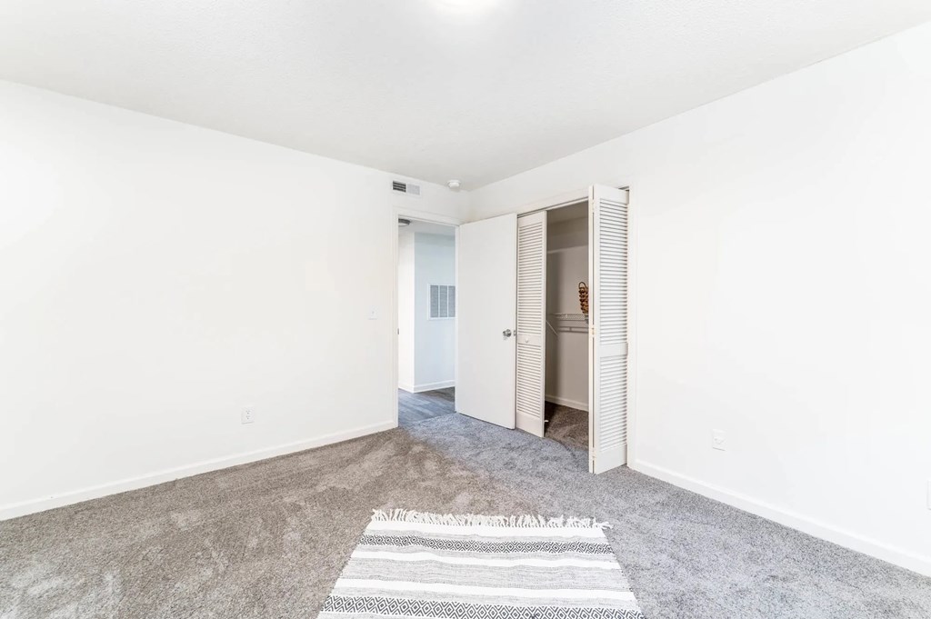 A room with a rug on the floor and a door on the right.