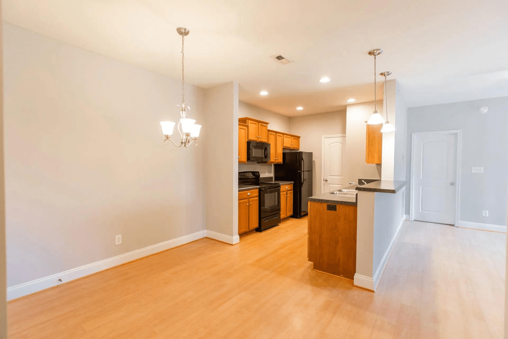 an empty living room and kitchen with wood floors