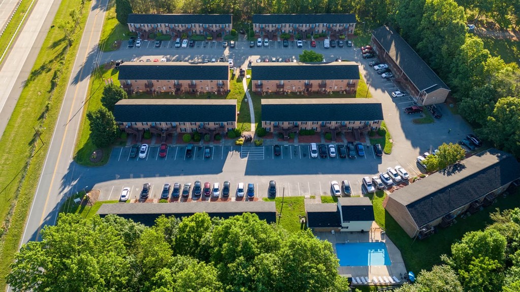 An aerial view of a parking lot with a swimming pool and a building.