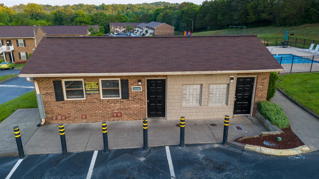 A small building with a brown roof and a parking lot in front.