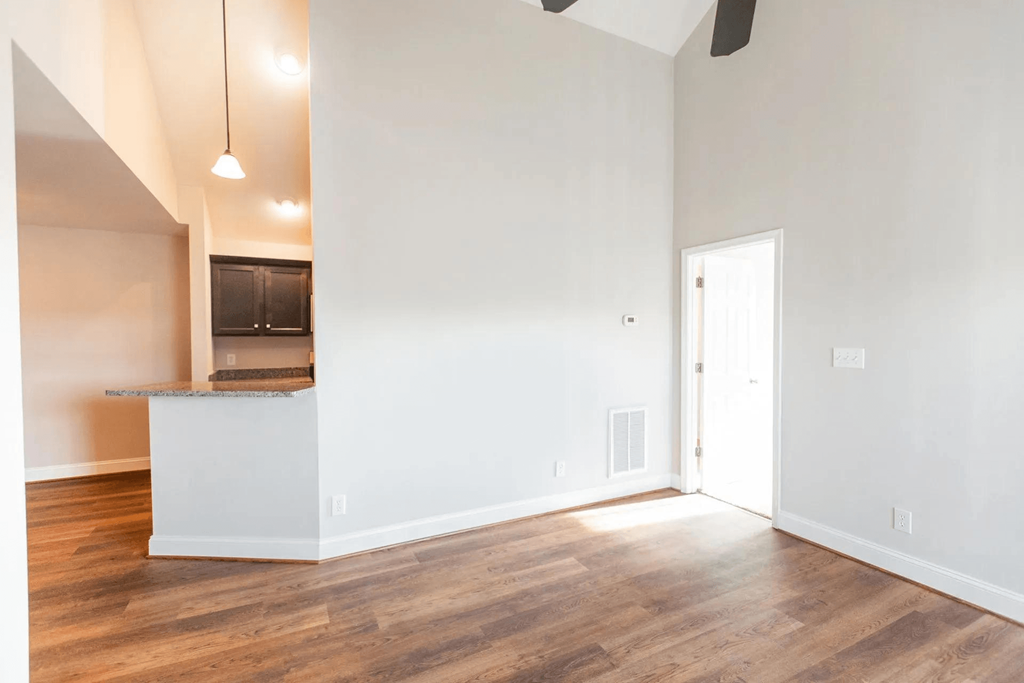 the living room and kitchen of an empty house with white walls and wood floors