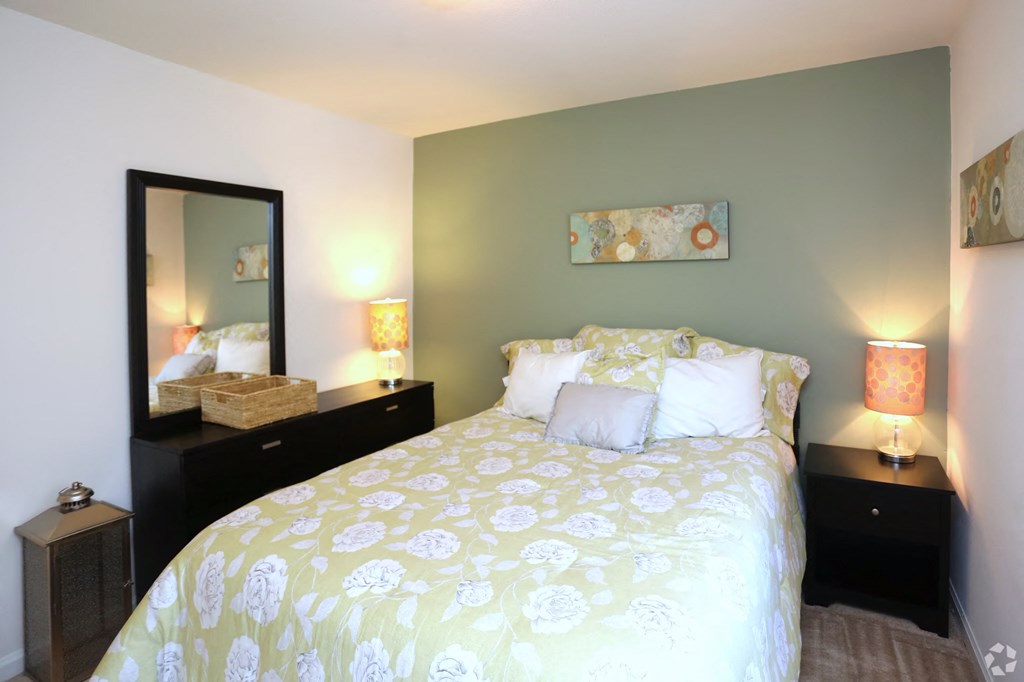 a bedroom with a yellow and white bed and a mirror