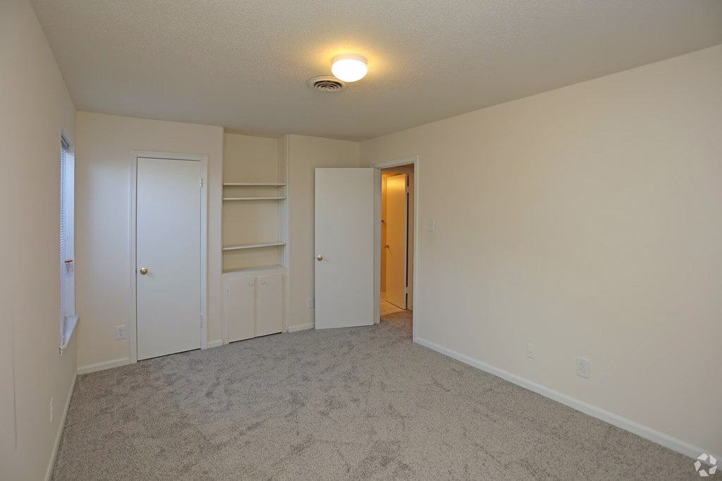 a empty living room with a closet and a door to a hallway