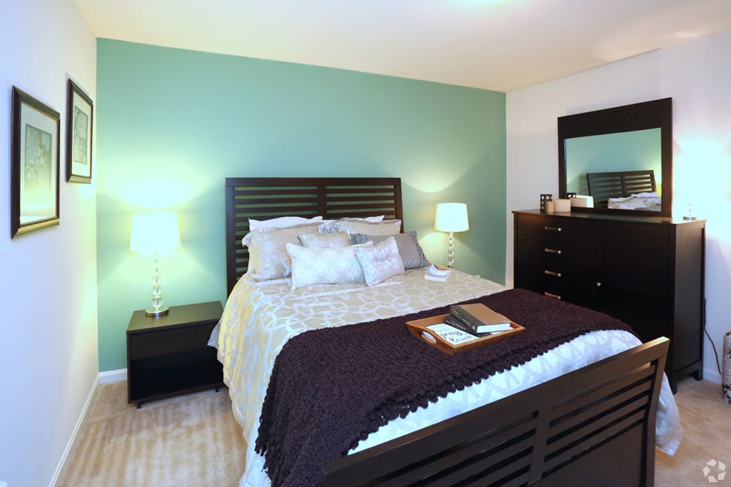 a bedroom with a bed and a dresser and a mirror