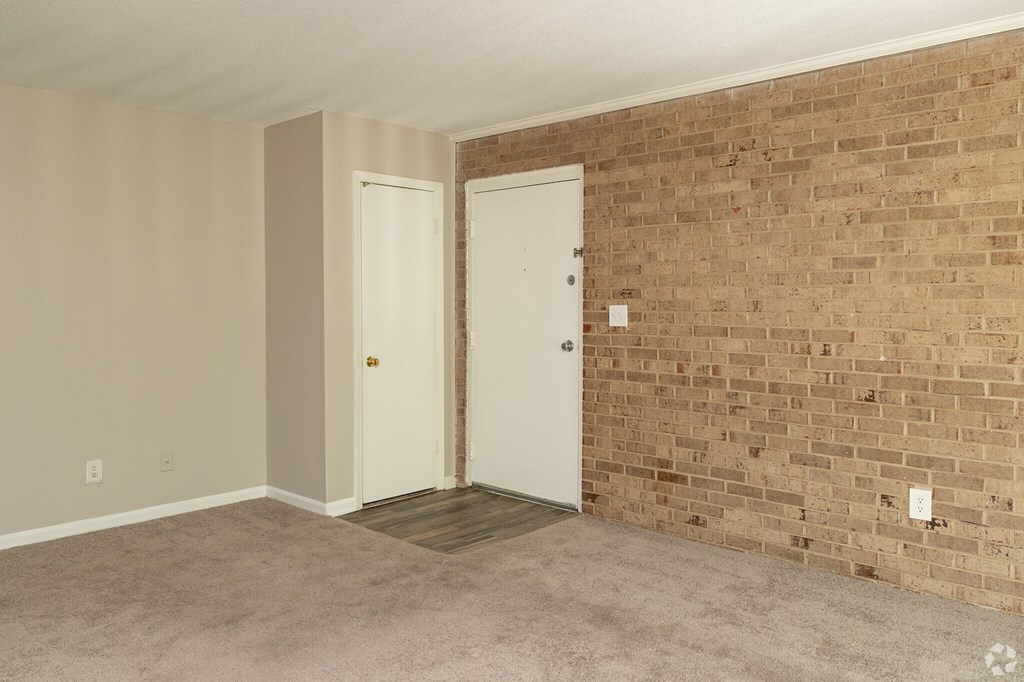 an empty living room with a brick wall and two doors