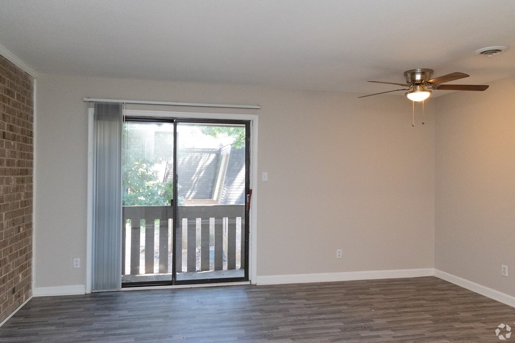an empty living room with a sliding glass door and a ceiling fan