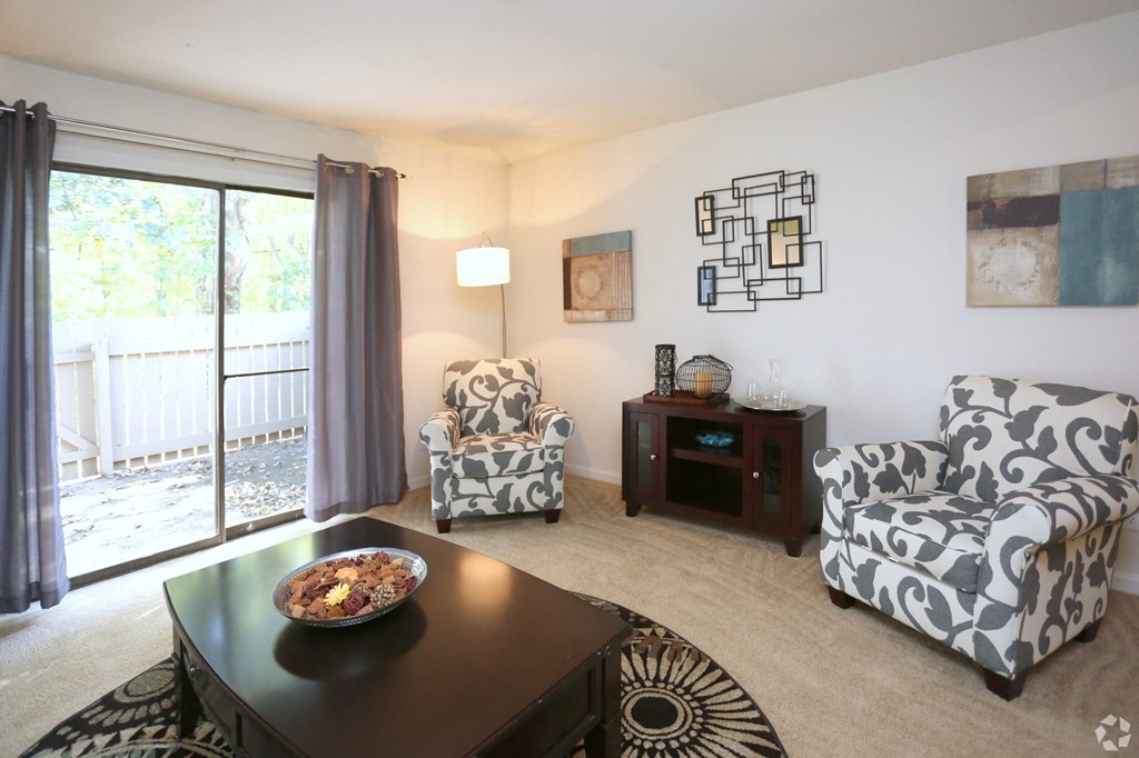 a living room with chairs and a table and a sliding glass door