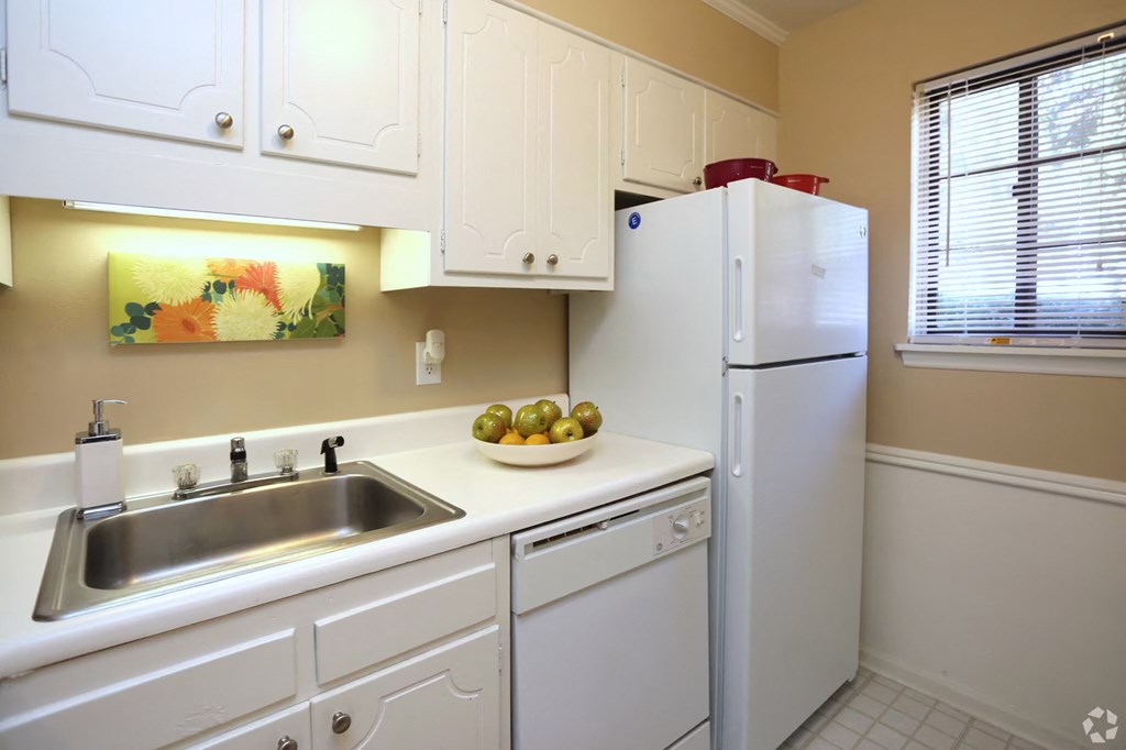 a kitchen with white cabinets and a sink and a refrigerator