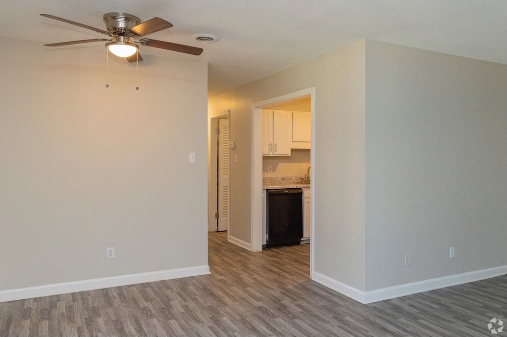 an empty living room and kitchen with a ceiling fan
