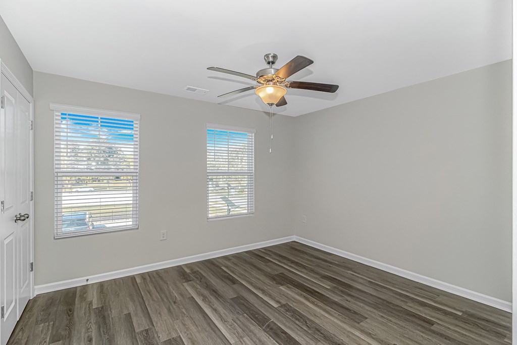 A room with a ceiling fan and wooden flooring.