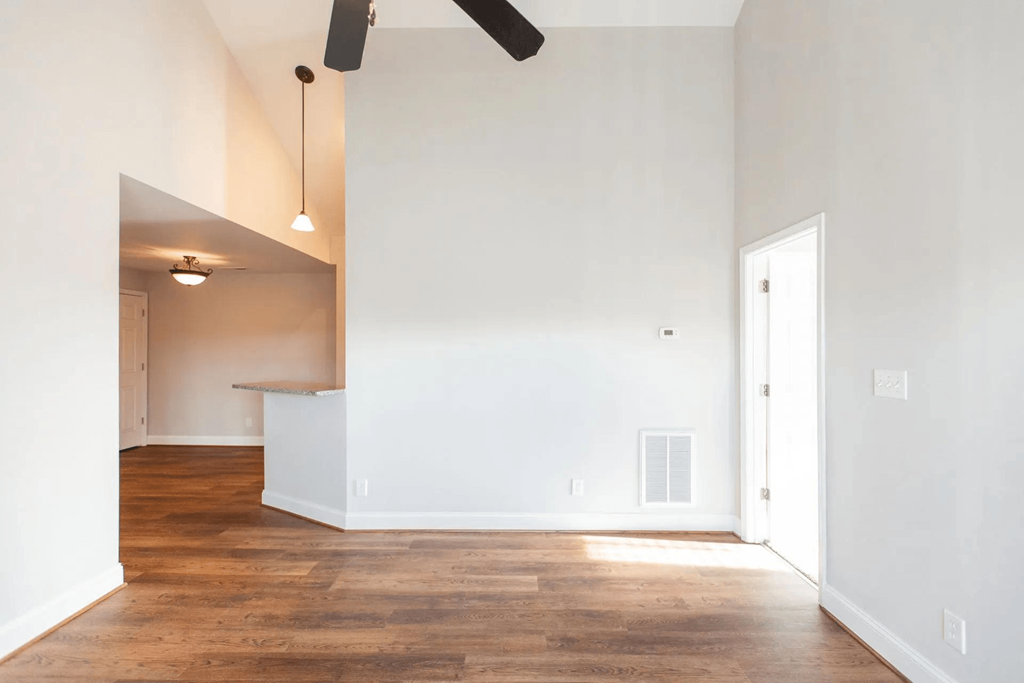 a living room and kitchen with white walls and wood floors