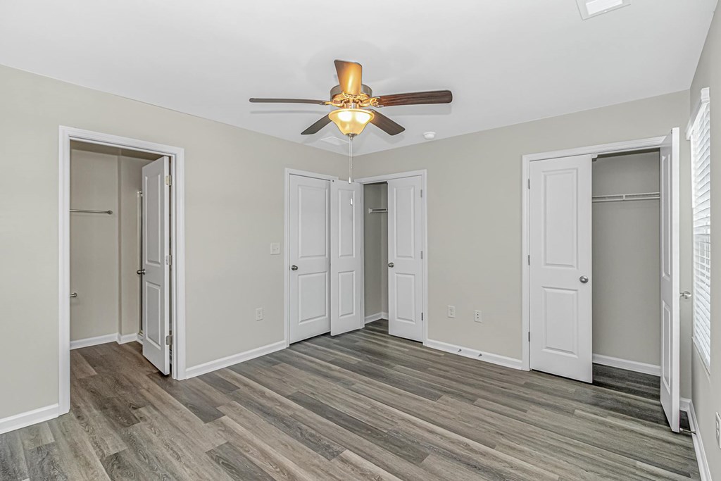 A room with a ceiling fan and wood flooring.
