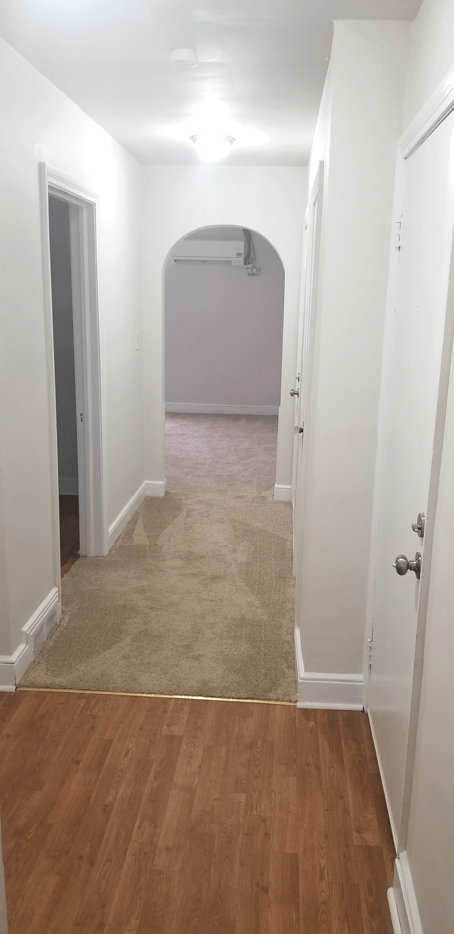 an empty hallway with a wood floor and white walls