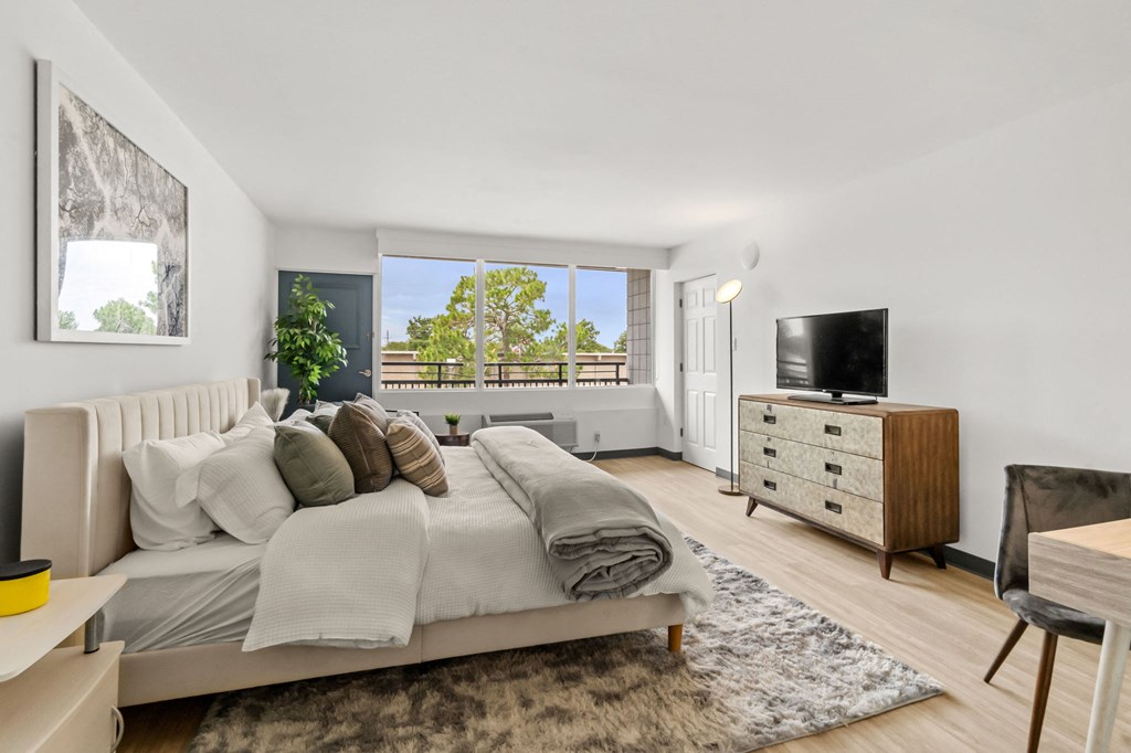 A bedroom with a large bed, a chair, and a TV.
