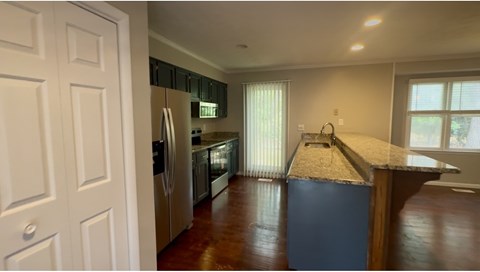 A kitchen with a refrigerator, oven, and sink.