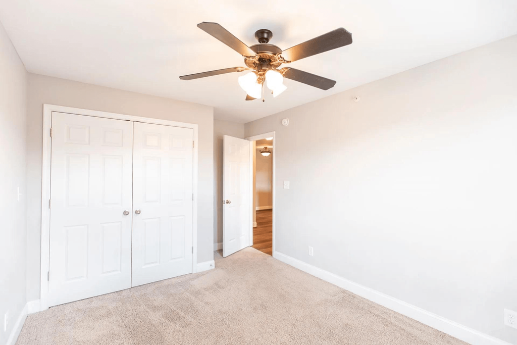 a bedroom with a ceiling fan and a door to a closet
