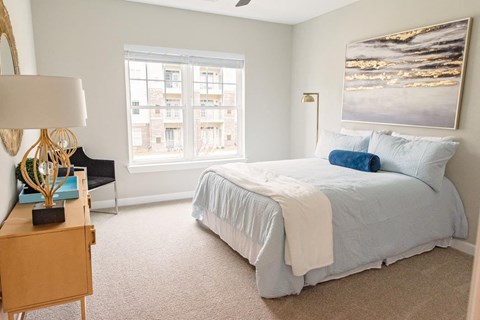 A bedroom with a bed, a nightstand, and a window.