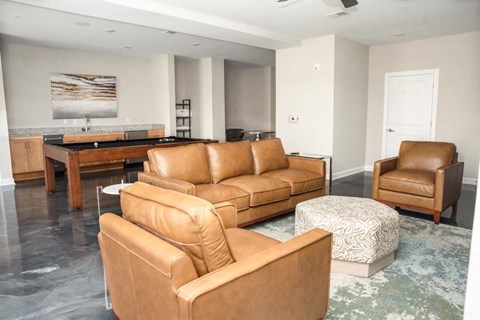 A living room with brown leather furniture and a painting on the wall.