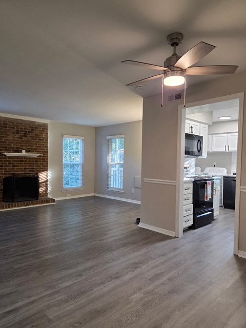 A room with a ceiling fan and a brick fireplace.