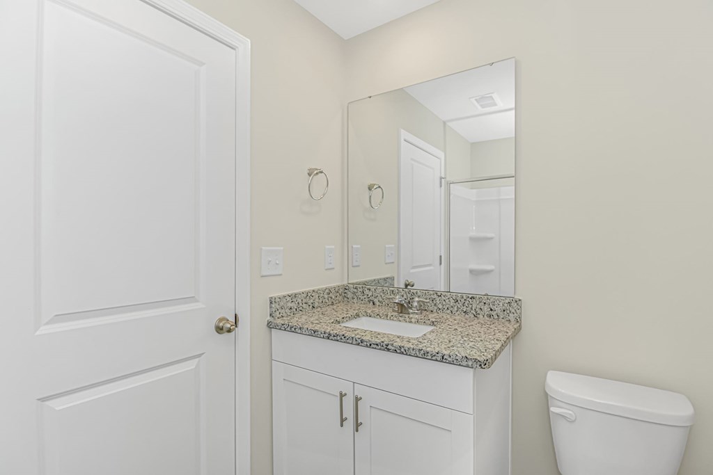 A bathroom with a granite countertop and white fixtures.