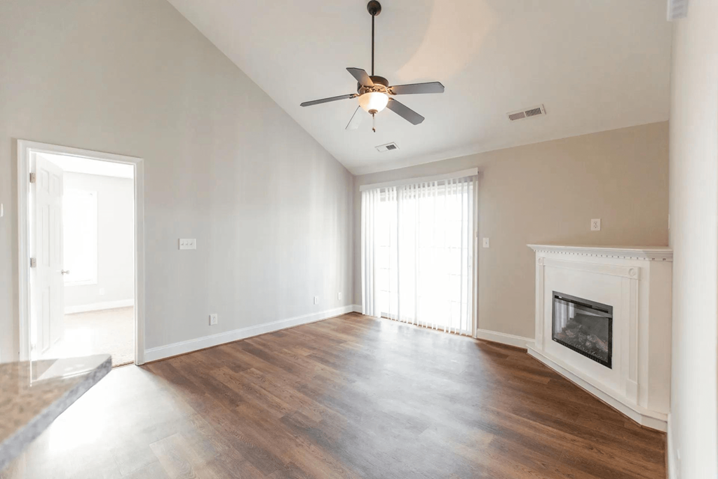 an empty living room with a ceiling fan and a fireplace